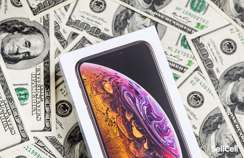 An iPhone box sat on a pile of dollar bills