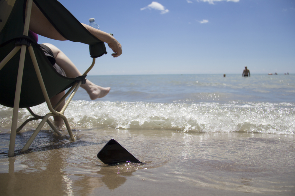 smartphone submerged in water on the beach